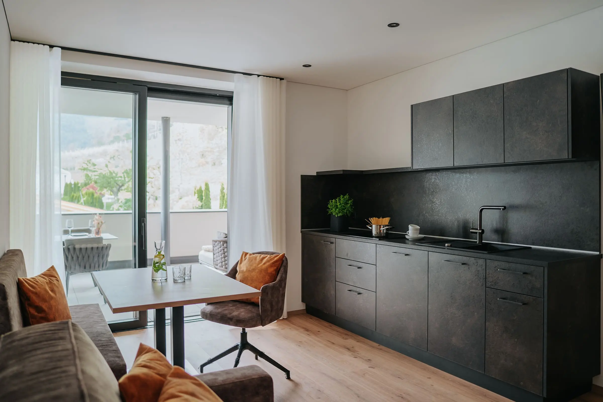 Cucina a vista moderna, accogliente zona pranzo e portafinestra che dà sulla terrazza, nell'Appartamento Romantica dei Montoni Chalets a Prato allo Stelvio.