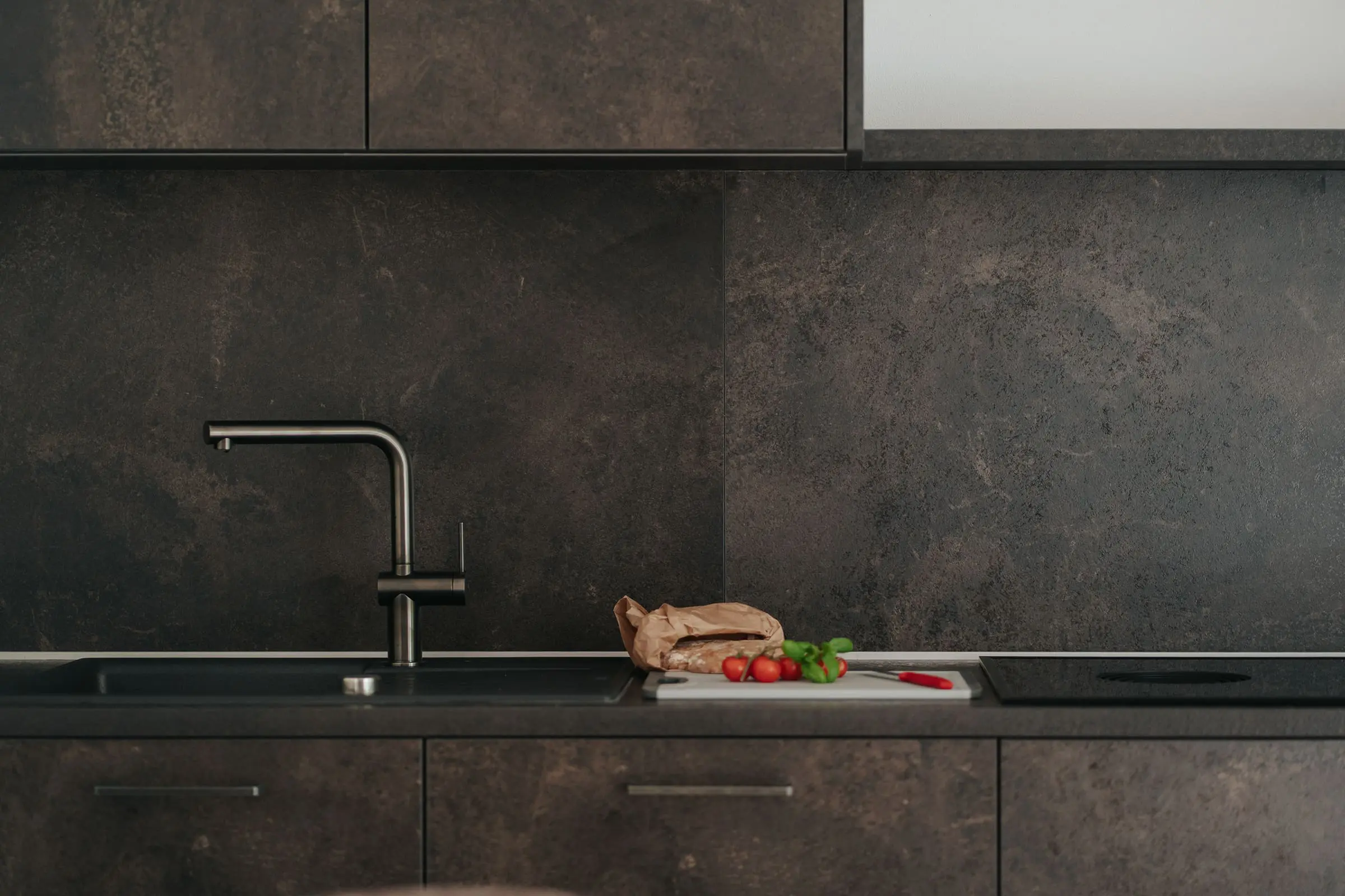 Chopping board with tomatoes and basil in the modernly designed kitchen of the Exclusiva Apartment at the Montoni Chalets in Prad am Stilfserjoch.