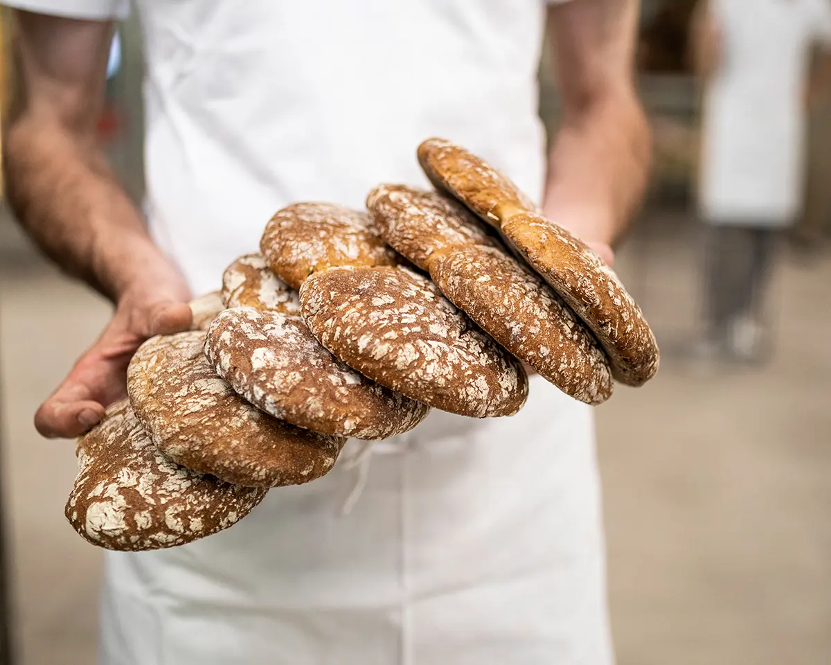 Bäcker präsentiert traditionelle Südtiroler Brötchen.