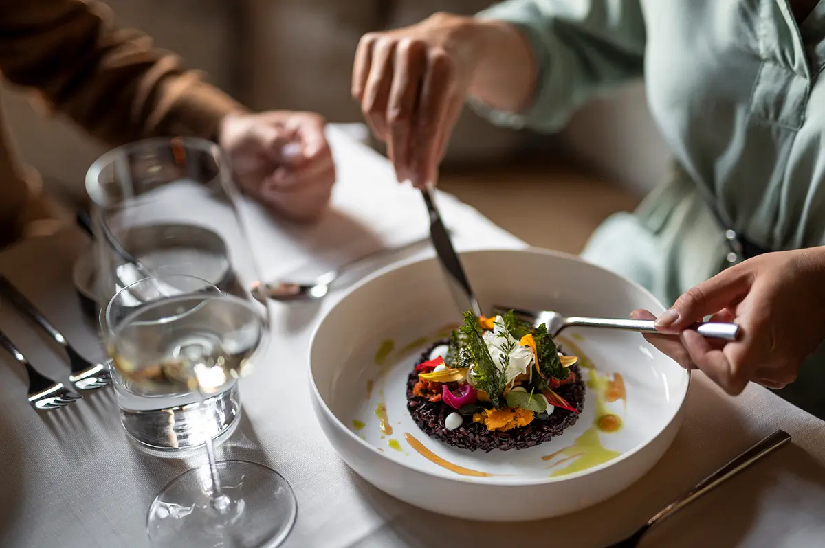 Zwei Personen sitzen an einem edel gedeckten Tisch in einem Restaurant im Vinschgau.