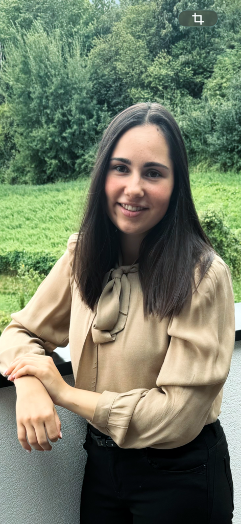 Lea Tondelli steht vor einer grünen Wiese mit Bäumen.