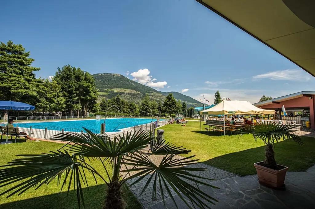 Liegewiese, Pool, Sitzbänke und Gastronomie im Erlebnisbad Prad mit einer beeindruckenden Aussicht auf die Berge.